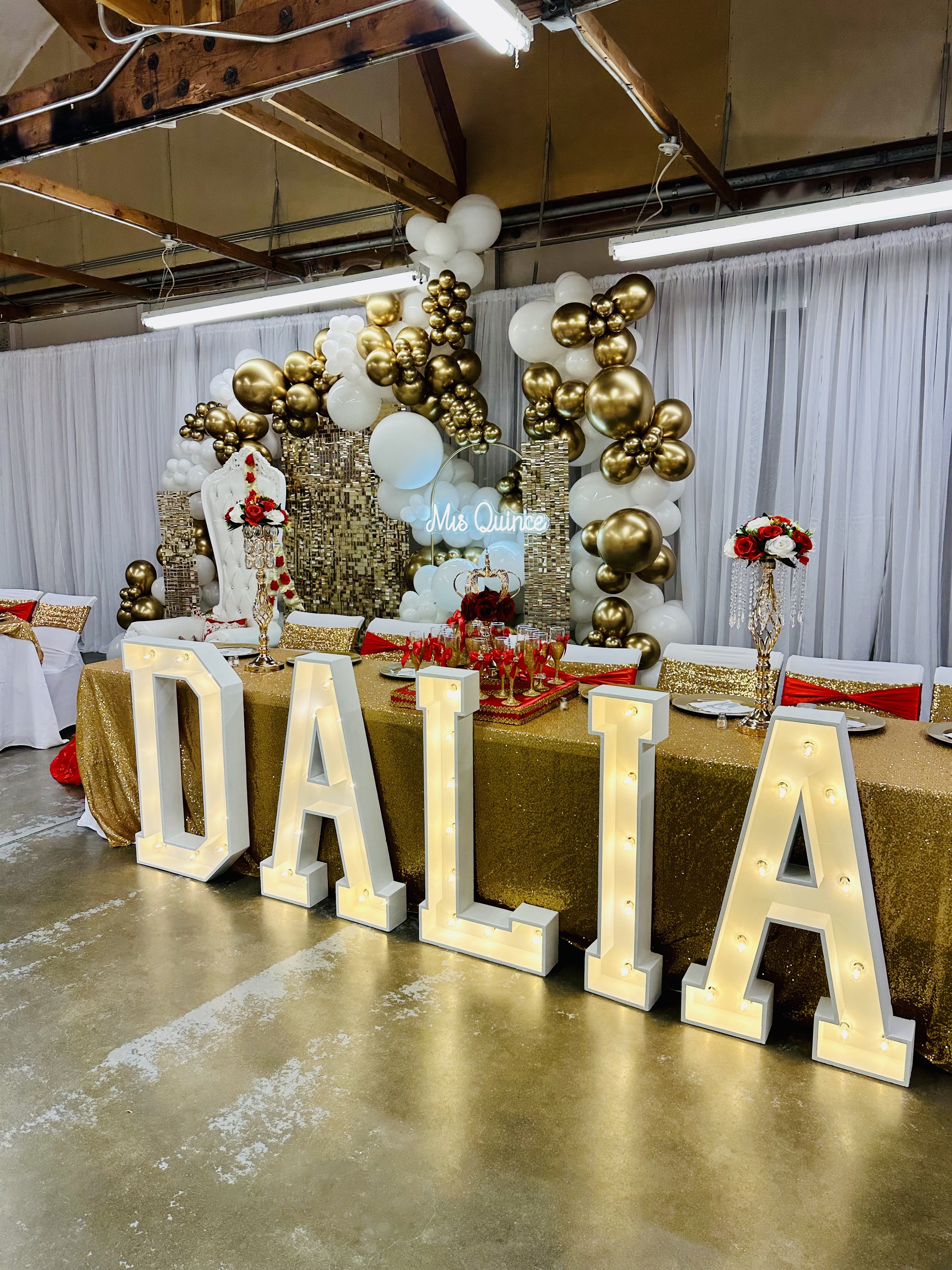 Quinceañera reception with gold sequin linens, lit marquee letters spelling Dalia, a white and gold balloon arch and a Mis Quince neon sign, set up by NCW Event Rentals in Eastern Washington
