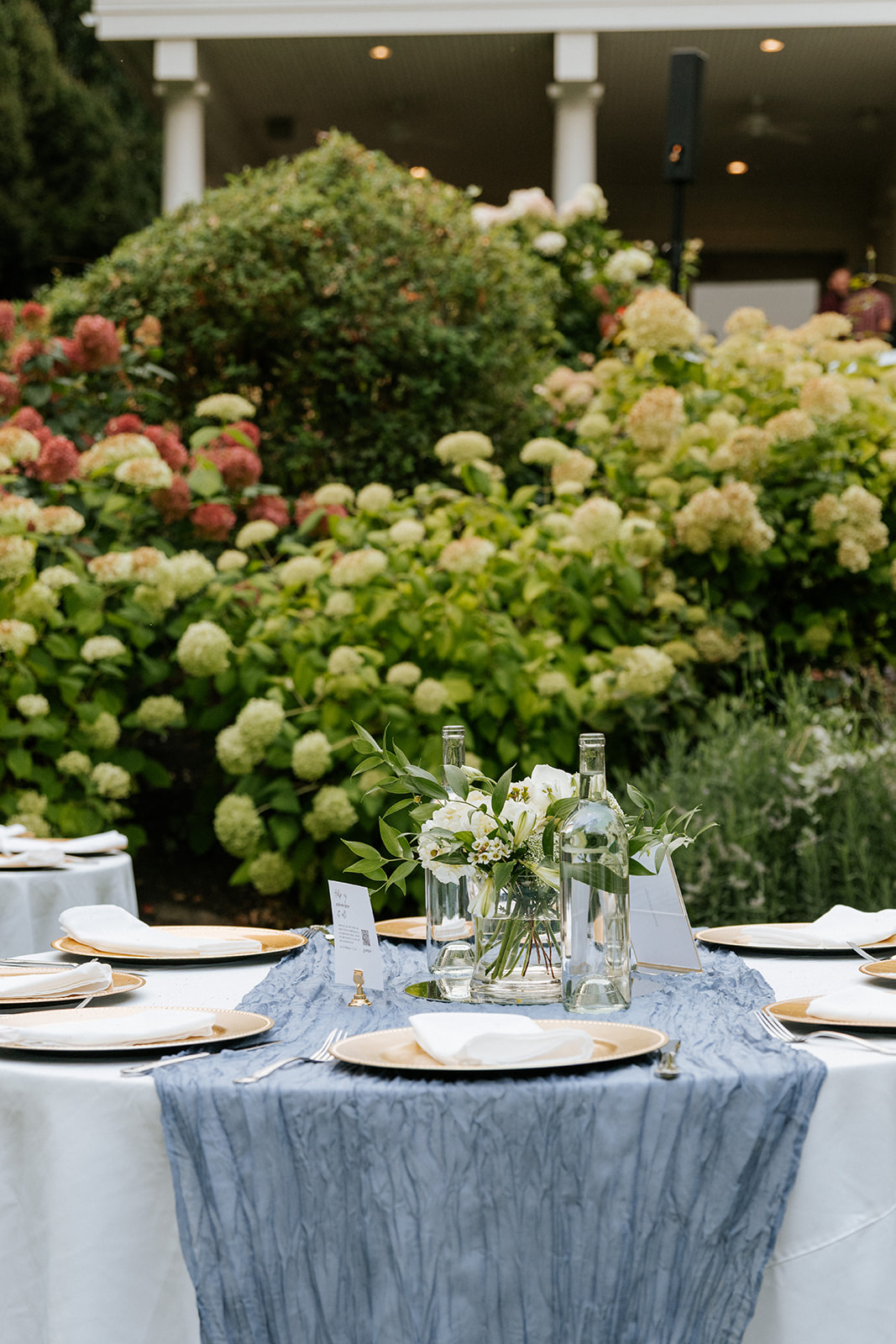 Outdoor reception table with blue runner, gold charger rentals and hydrangeas in Eastern Washington
