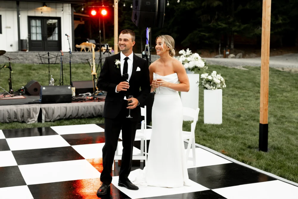 Groom giving a speech on a black and white dance floor during an outdoor wedding reception in Cle Elum, Washington