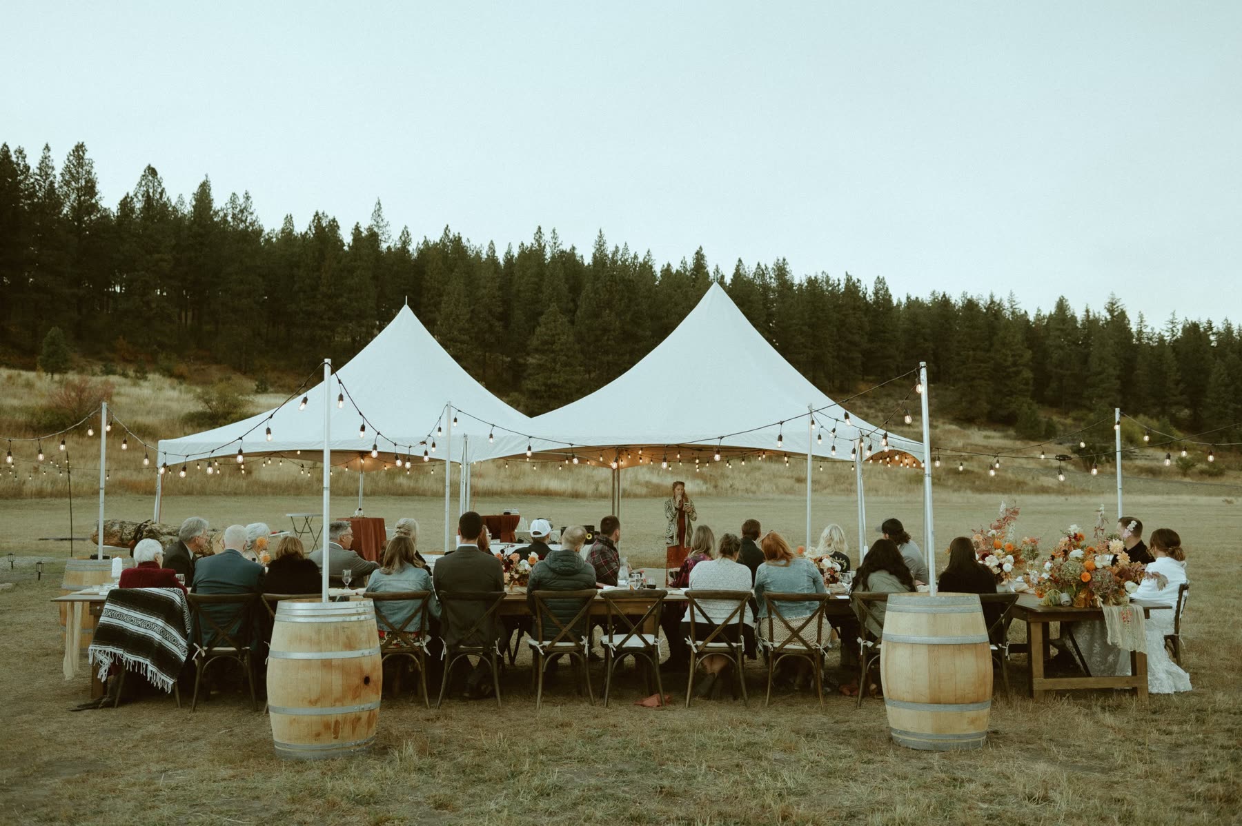 Farmhouse tables set for dinner under a sailcloth tent at a Washington wedding reception
