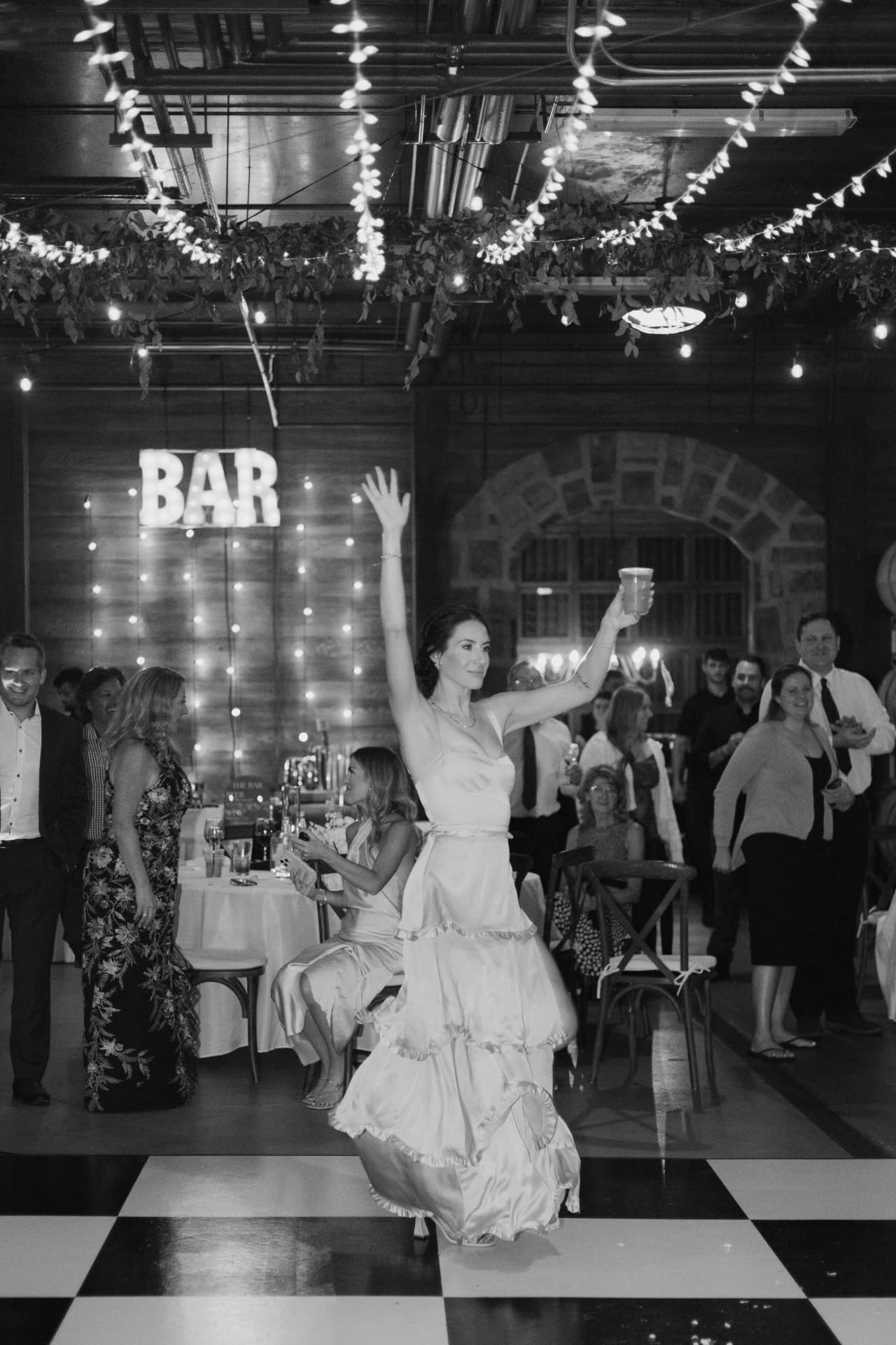 Black and white photo of a bride celebrating on a checkered dance floor rental at Swiftwater Cellars in Cle Elum