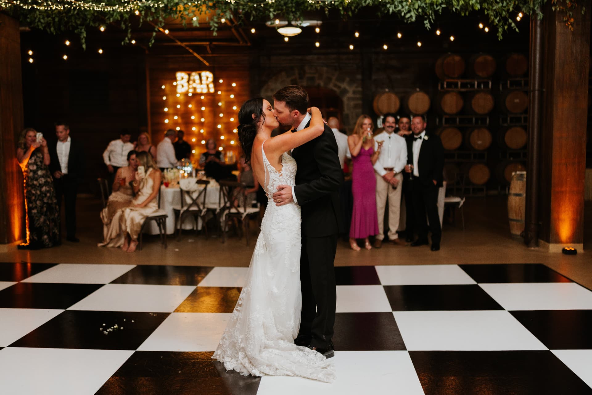 Bride and groom kissing on a black and white dance floor in the barrel room at Swiftwater Cellars, Cle Elum